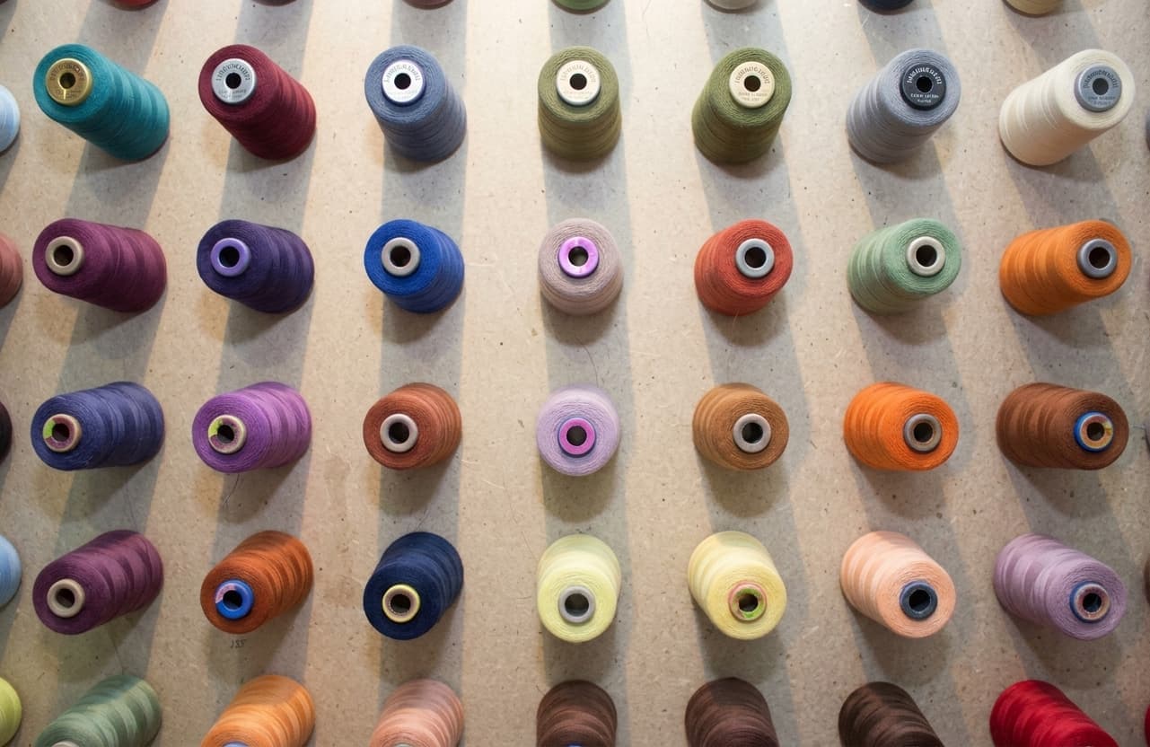 Rows of colourful thread spools racked on a factory wall